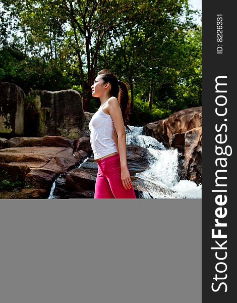 Outdoor waterfall young woman stretching her body. Outdoor waterfall young woman stretching her body
