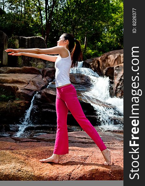 Outdoor waterfall young woman stretching her body. Outdoor waterfall young woman stretching her body