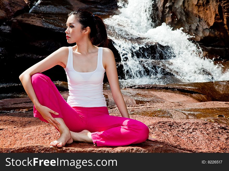 Outdoor waterfall young woman stretching her body. Outdoor waterfall young woman stretching her body