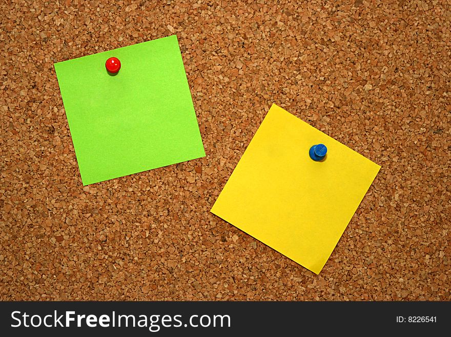 Green and yellow note in cork board. Green and yellow note in cork board