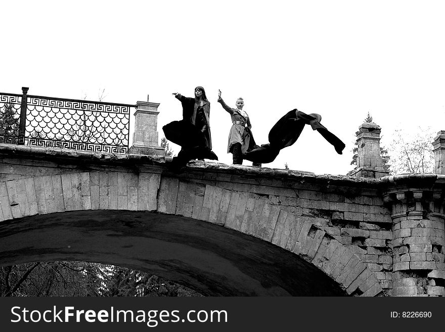 Two girls with flapping fabric in old bridge. Two girls with flapping fabric in old bridge