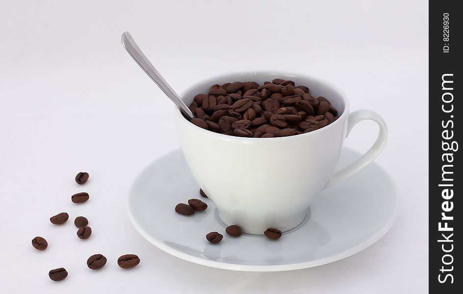 Seeds of coffee poured into the cup on a white background. Seeds of coffee poured into the cup on a white background