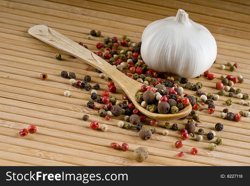 Wooden spoon full of colorful aromatic peppers and a garlic. Wooden spoon full of colorful aromatic peppers and a garlic