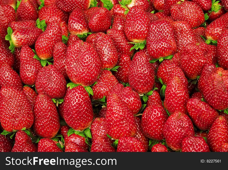 A lot of red strawberries with green leafs