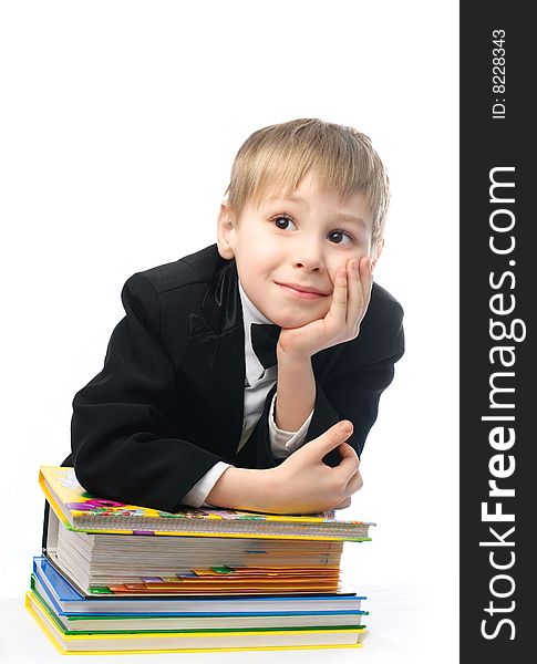 Bored schoolboy sitting by the table with a lot of books and unwilling to do homework