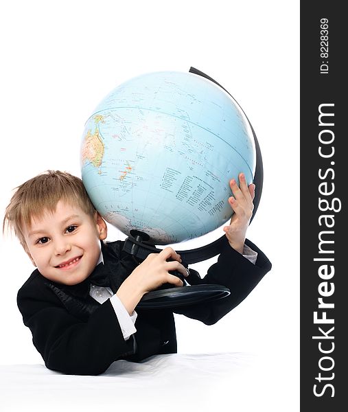 Happy schoolboy sitting by the table with a big globe in his hands. Happy schoolboy sitting by the table with a big globe in his hands