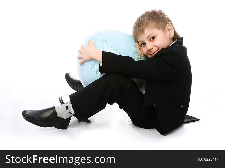 Happy little schoolboy sitting on the floor and embracing a big globe. Happy little schoolboy sitting on the floor and embracing a big globe