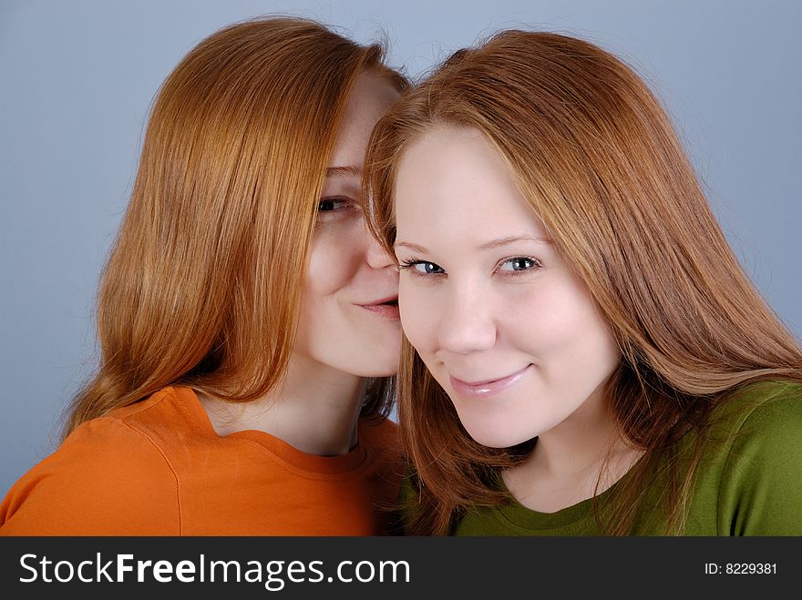 Two redhead young woman are secretive and smile. Two redhead young woman are secretive and smile