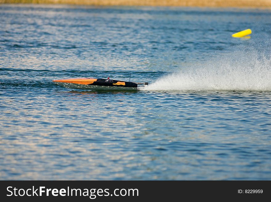 An R/C model boat takes practice laps around a course layed out with yellow pilings. An R/C model boat takes practice laps around a course layed out with yellow pilings