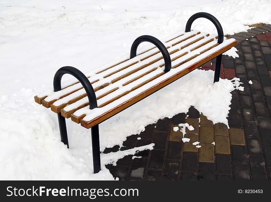 A bench on the snowfield in the park.