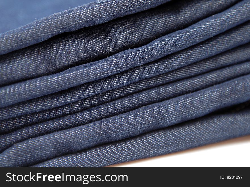 Folded pile of blue denim jeans on white background. Folded pile of blue denim jeans on white background
