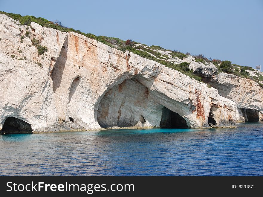 Rocks on Zakynthos Island - Greece. Blue sea, yacht and white sandy beach. Rocks on Zakynthos Island - Greece. Blue sea, yacht and white sandy beach.
