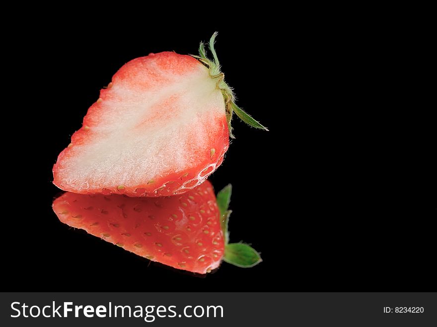 Half strawberry isolated on black with reflection