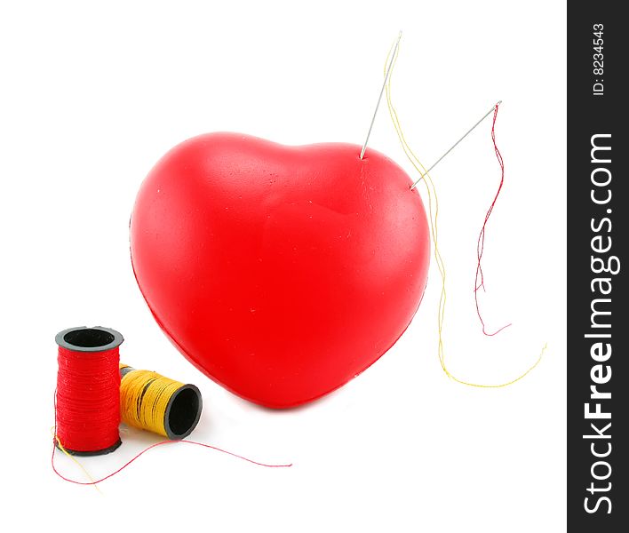 Heart shaped pincushion with spools and needles isolated on a white background