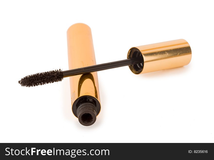 Gold mascara and brush on white background