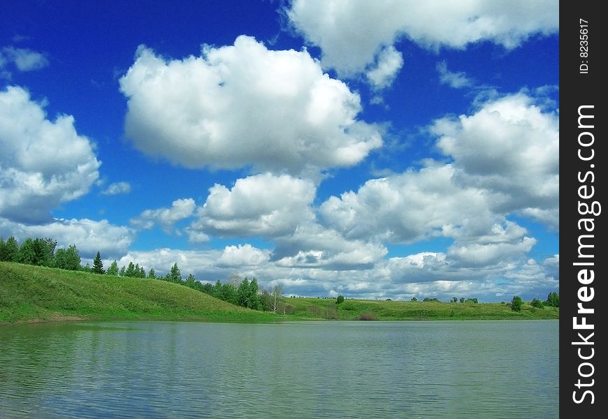 Pond and white clouds on blue sky
