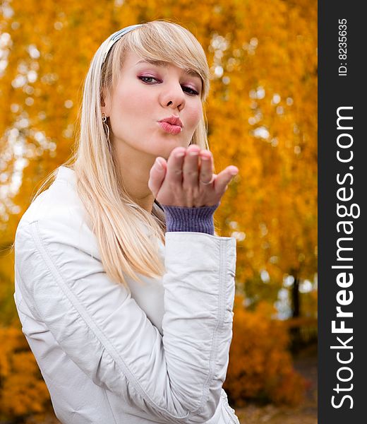 Pretty girl throwing a kiss - autumn park background - shallow DOF