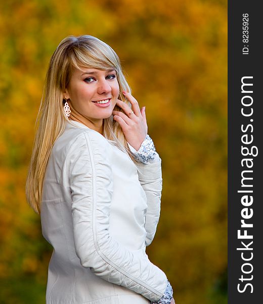 Pretty girl adjusting her hair on autumn park background - shallow DOF