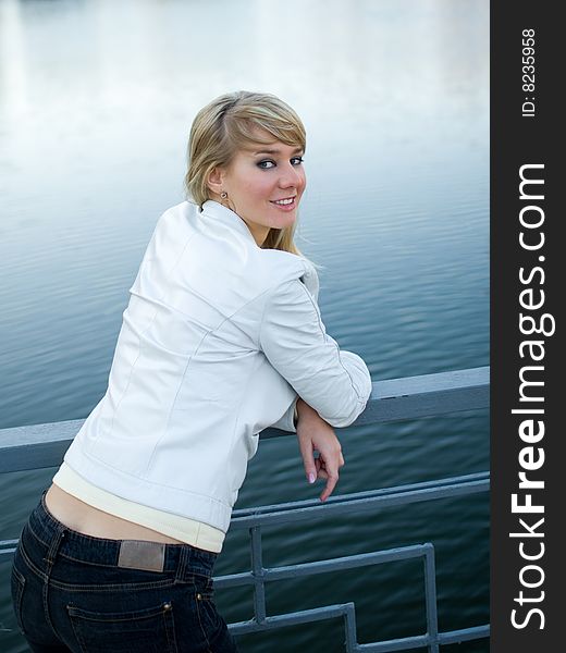 Pretty girl in white jacket near fence of a bridge - shallow DOF