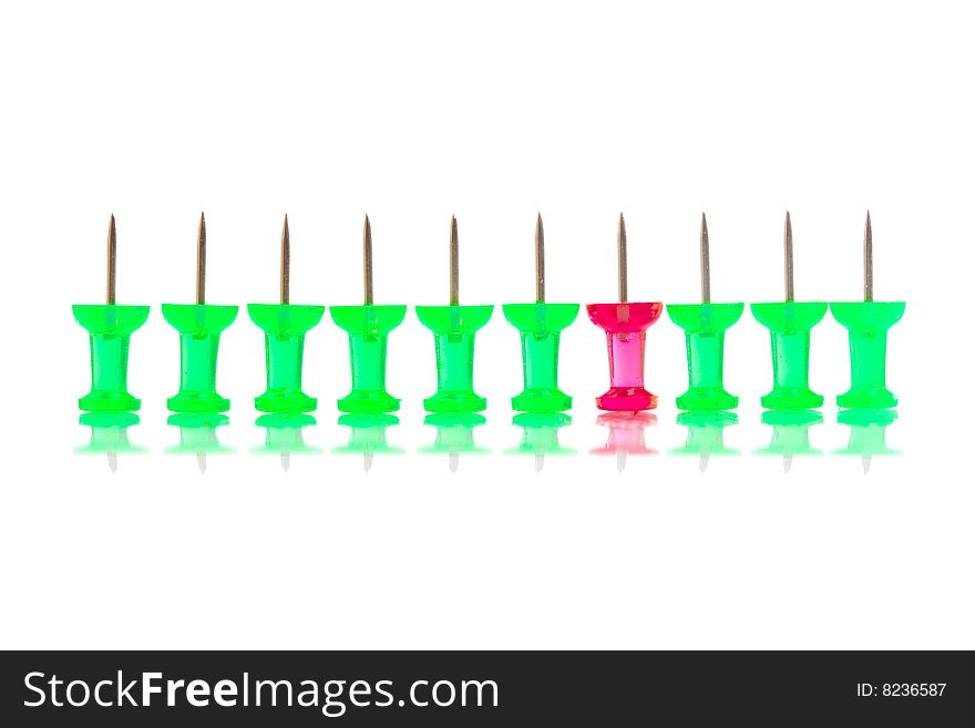 A red push pin stands in a row of green ones. A red push pin stands in a row of green ones