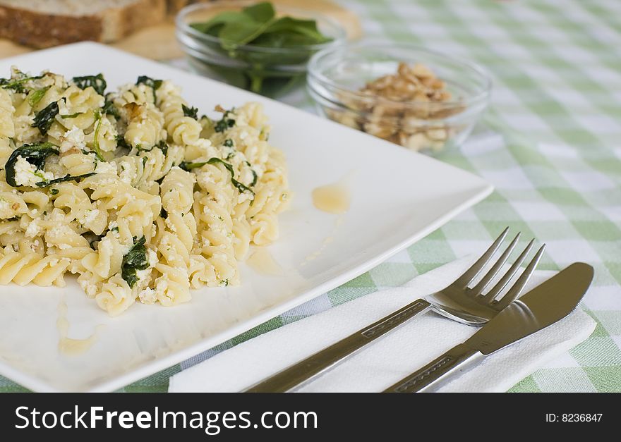 A plate of pasta with walnut, spinach and ricotta served with a glass of white wine. A plate of pasta with walnut, spinach and ricotta served with a glass of white wine