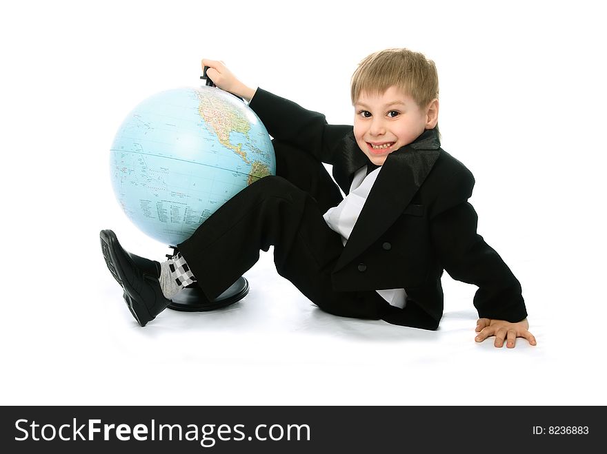 Happy schoolboy sitting on the floor with a big globe standing near him. Happy schoolboy sitting on the floor with a big globe standing near him