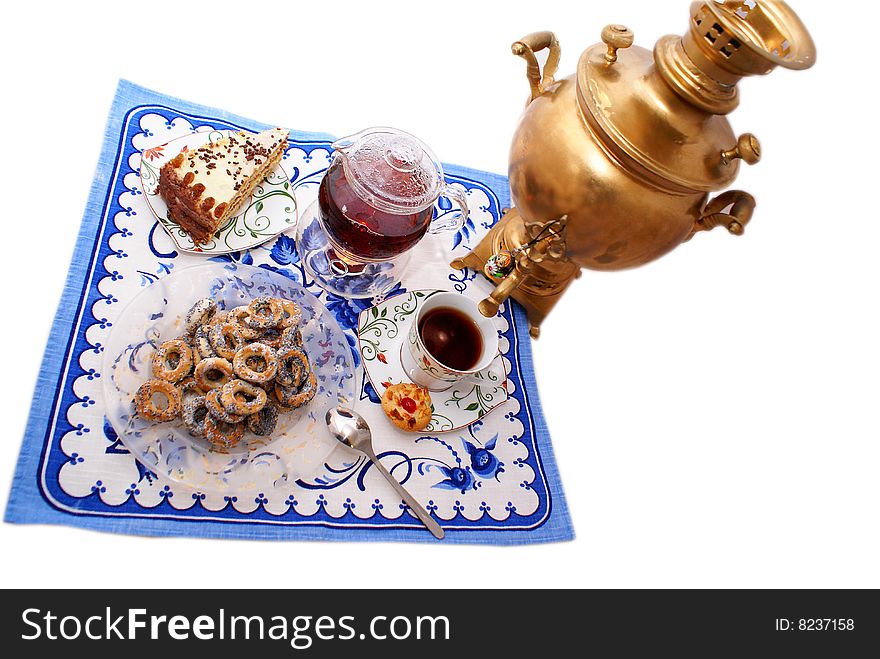 Teapot with a steep sealed tea, spilling a cup of tea, next a piece of home-made cake and Samovar. Teapot with a steep sealed tea, spilling a cup of tea, next a piece of home-made cake and Samovar.
