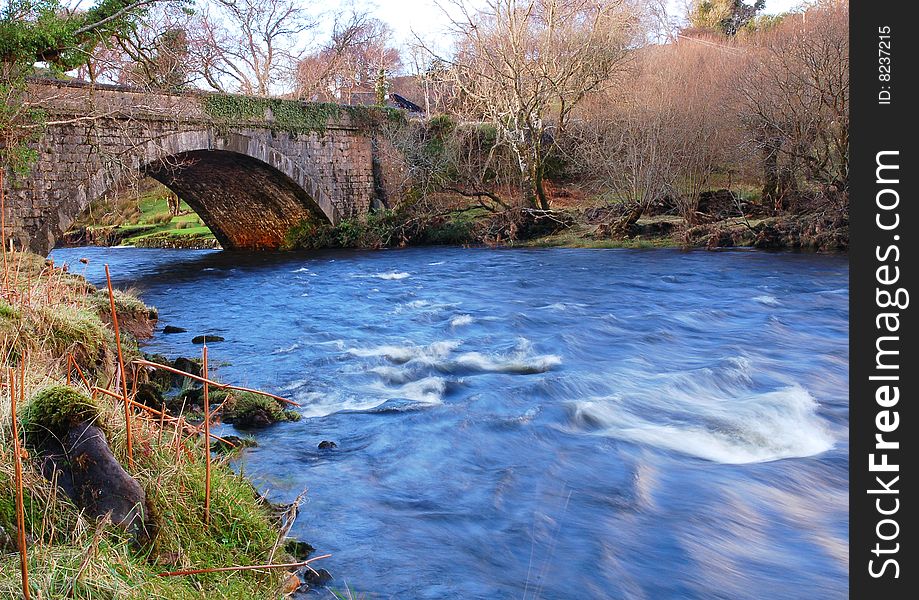 Bright blue water gushing under an old stone bridge. Bright blue water gushing under an old stone bridge.