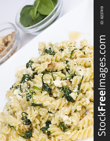 A plate of pasta with walnut, spinach and ricotta served with a glass of white wine. A plate of pasta with walnut, spinach and ricotta served with a glass of white wine