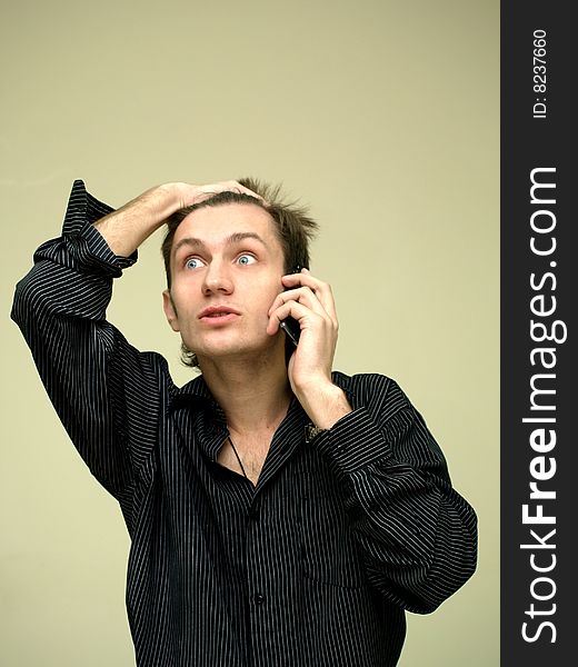 Young man in stressful condition is talking on the phone, grab hand on your head. Young man in stressful condition is talking on the phone, grab hand on your head