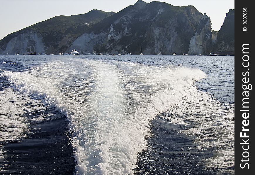 Wake of the boat with sea cliff