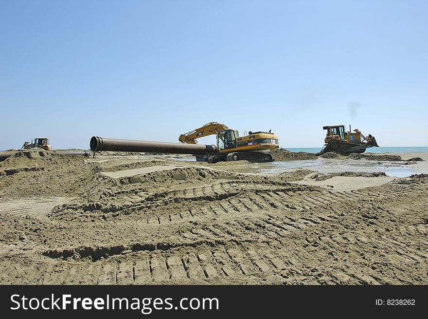 Caterpillars working on a beach by the sea