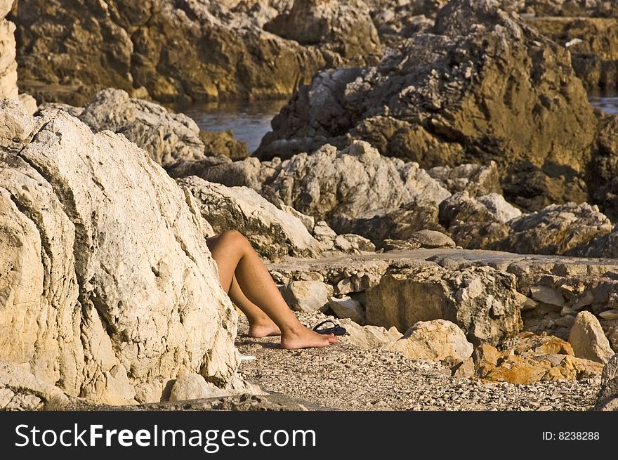 Legs of a woman tanning on the rocks