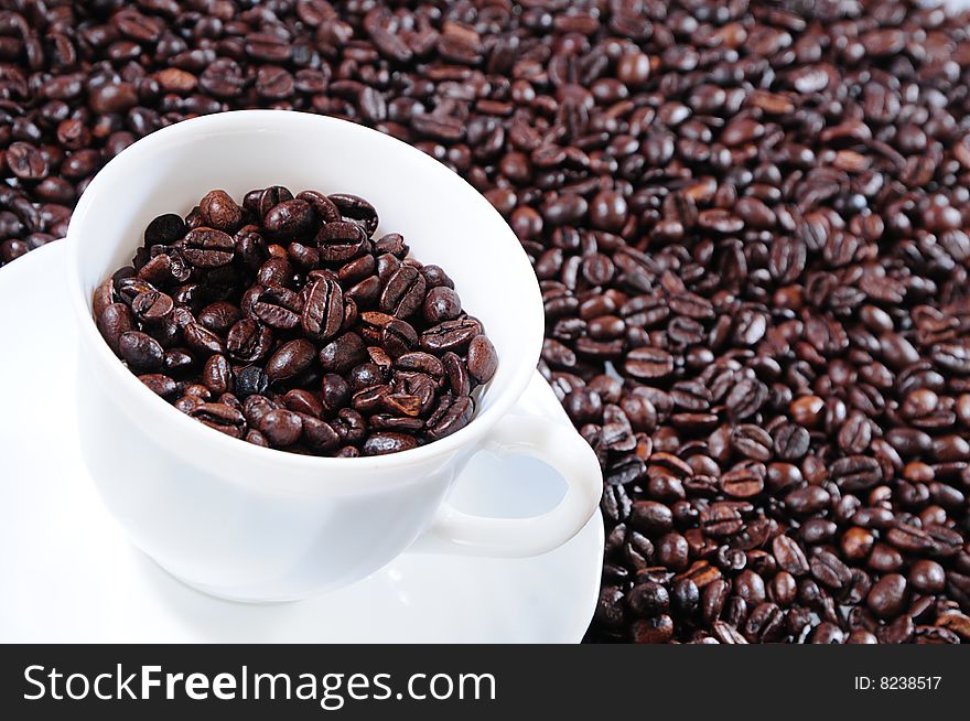 Coffee grains in a white cup on a background coffee grains