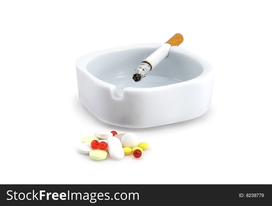 Decaying cigarette in an ashtray and tablets. Decaying cigarette in an ashtray and tablets.