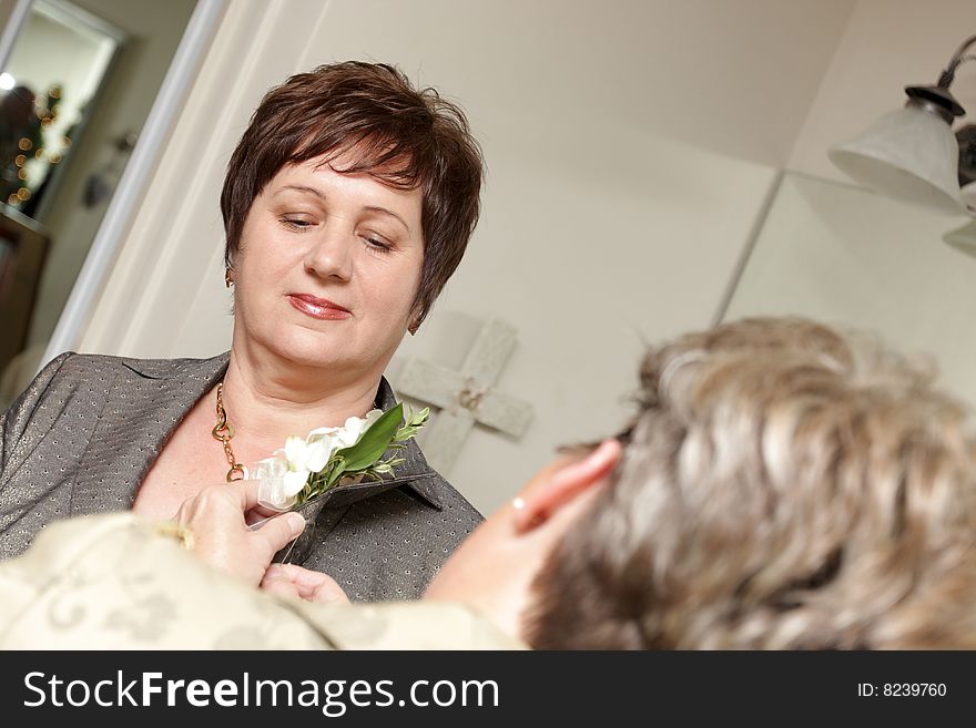 Woman pinning boutonniere on mother of the bride, wedding. Woman pinning boutonniere on mother of the bride, wedding