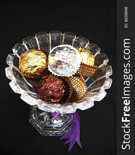 A gift of chocolate nuggets wrapped in different colored wrapping paper,in a bowl. A gift of chocolate nuggets wrapped in different colored wrapping paper,in a bowl
