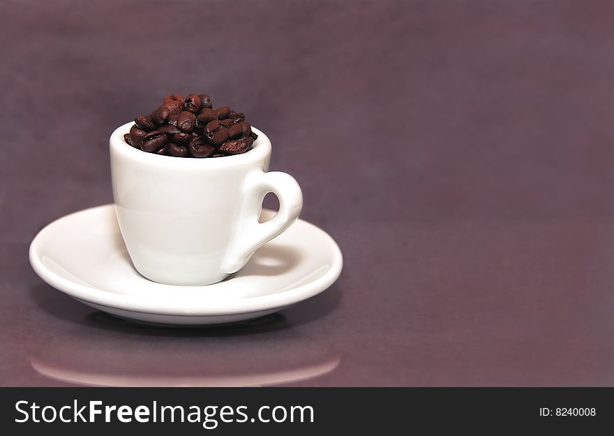 An espresso cup filled with roasted Colombian coffee beans.