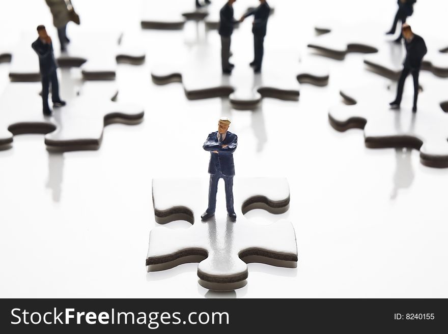 Businessman figurines placed with puzzle pieces. Businessman figurines placed with puzzle pieces