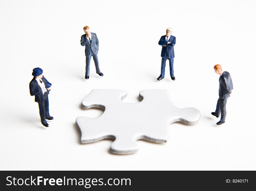 Four businessman figurines placed with a puzzle piece. Four businessman figurines placed with a puzzle piece