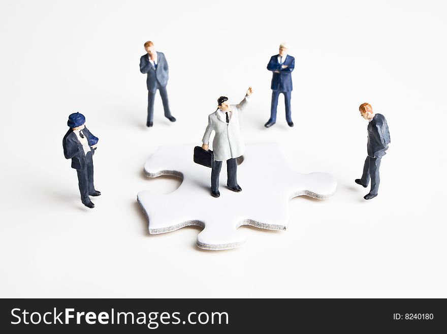 Five businessman figurines placed with a puzzle piece. Five businessman figurines placed with a puzzle piece