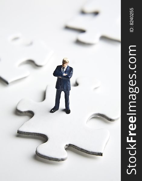 Businessman figurine placed on a puzzle piece. Businessman figurine placed on a puzzle piece