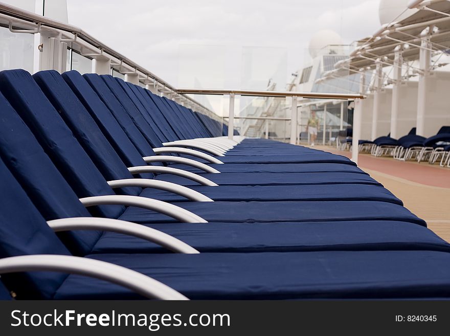 Blue chaise lounges lined up on the deck of a cruise ship. Blue chaise lounges lined up on the deck of a cruise ship