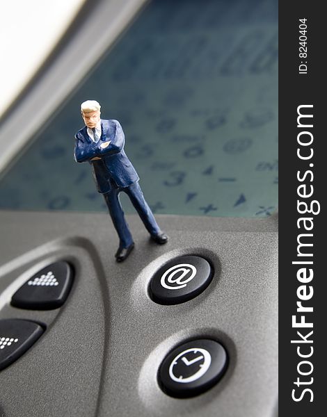 Businessman figurine standing on a PDA. Businessman figurine standing on a PDA
