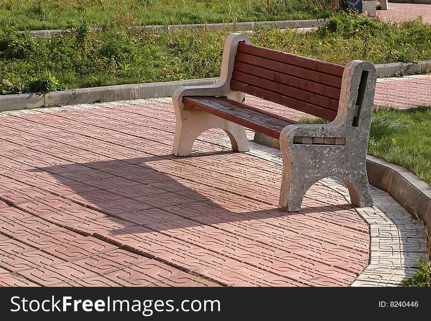 Bench and its shade on sidewalk. Bench and its shade on sidewalk