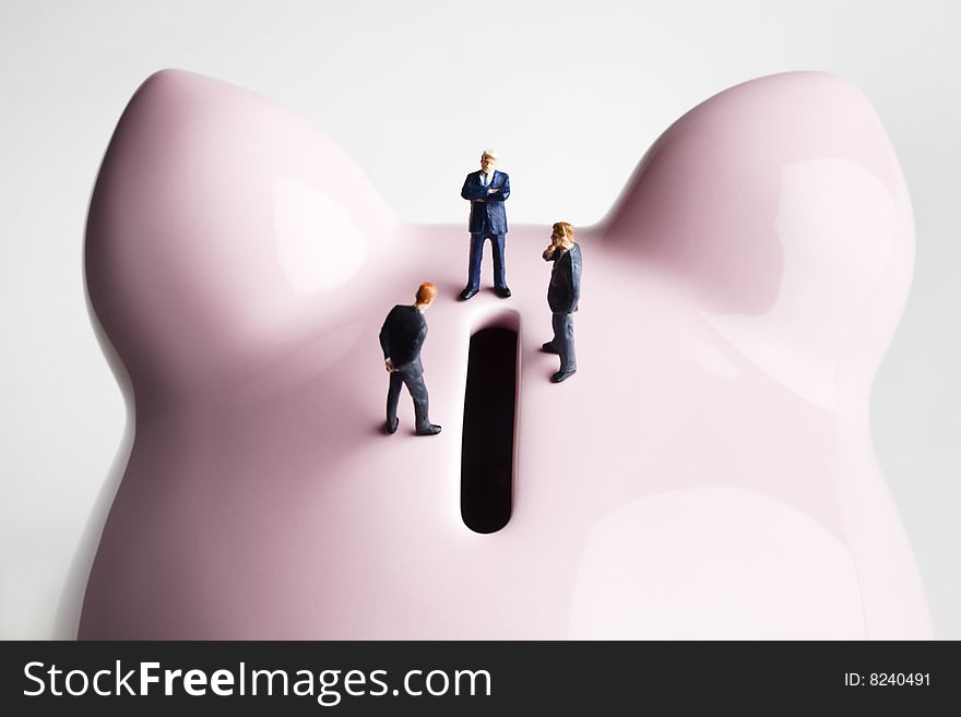 Businessman figurines placed on a piggy bank. Businessman figurines placed on a piggy bank