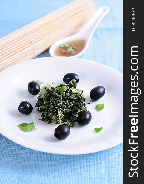 Spinach with black olives on blue background