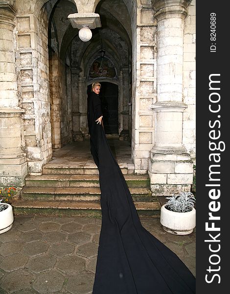 Lovely woman beside old castle in black fabric