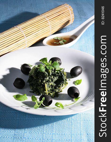 Spinach with black olives on blue background