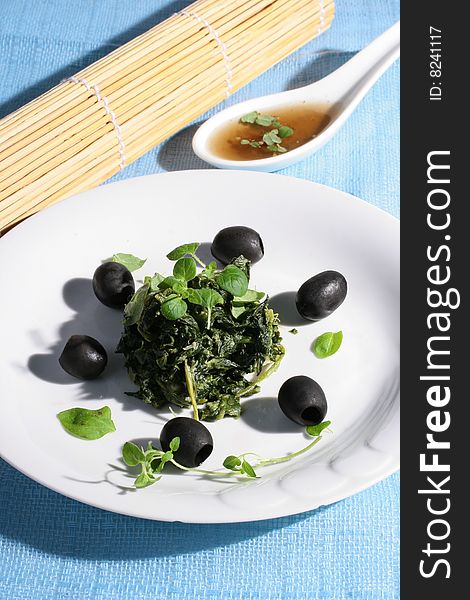 Spinach with black olives on blue background